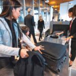 A woman preparing her luggage to go through the security scanner at the airport.