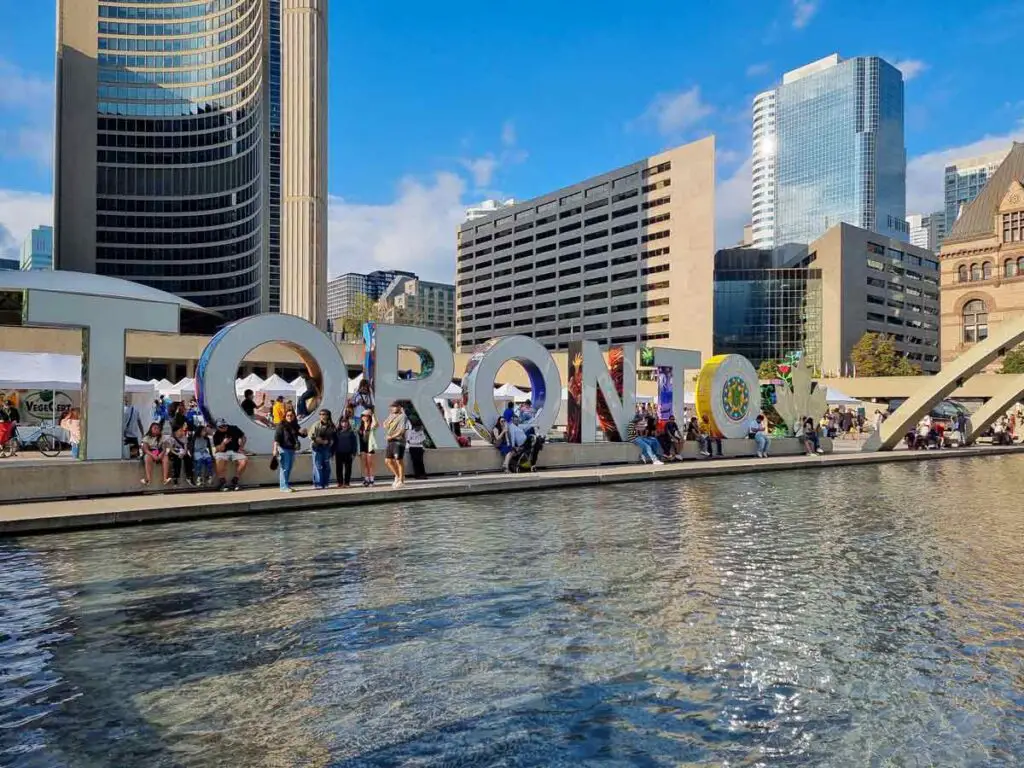 The Toronto sign facing a large fountain on a sunny day pin