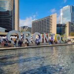 The Toronto sign facing a large fountain on a sunny day pin