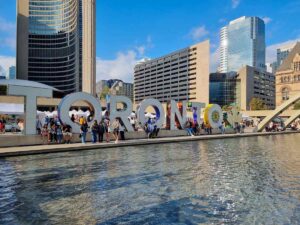 The Toronto sign facing a large fountain on a sunny day pin