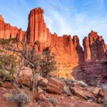 Red rocks rising from a canyon towards the blue sky.