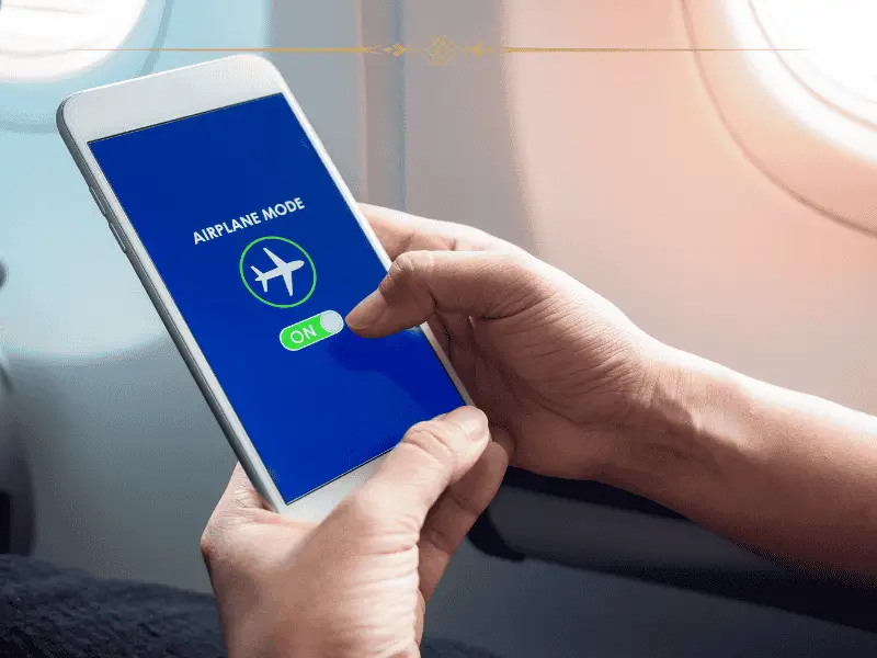 A close-up of a pair of hands holding a phone, turning airplane mode on