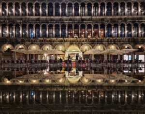 The columns in Piazza San Marco reflecting in the water below, at night, creating a mirror on the floor.
