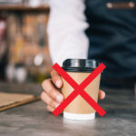 Major Airline Implements Strict No-Coffee Policy for Flight Crews A close-up on a barista hand hanging in a coffee cup, with a red x on it.