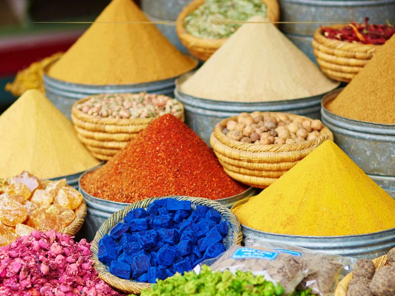 A photo of spices in the souk in Marrakech. They all have very vibrant colours and are arranged in a cone shape in their containers.
