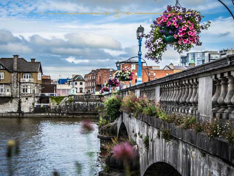 A picturesque city in Ireland, on the shore of a river, crossed by a stone bridge.