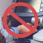 Using ATMs on Vacation? This 5-Second Trick Will Save You Hundreds of $ A stop sign over a photo of someone withdrawing money from an atm.