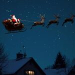 Santa flying over houses covered with snow, at night