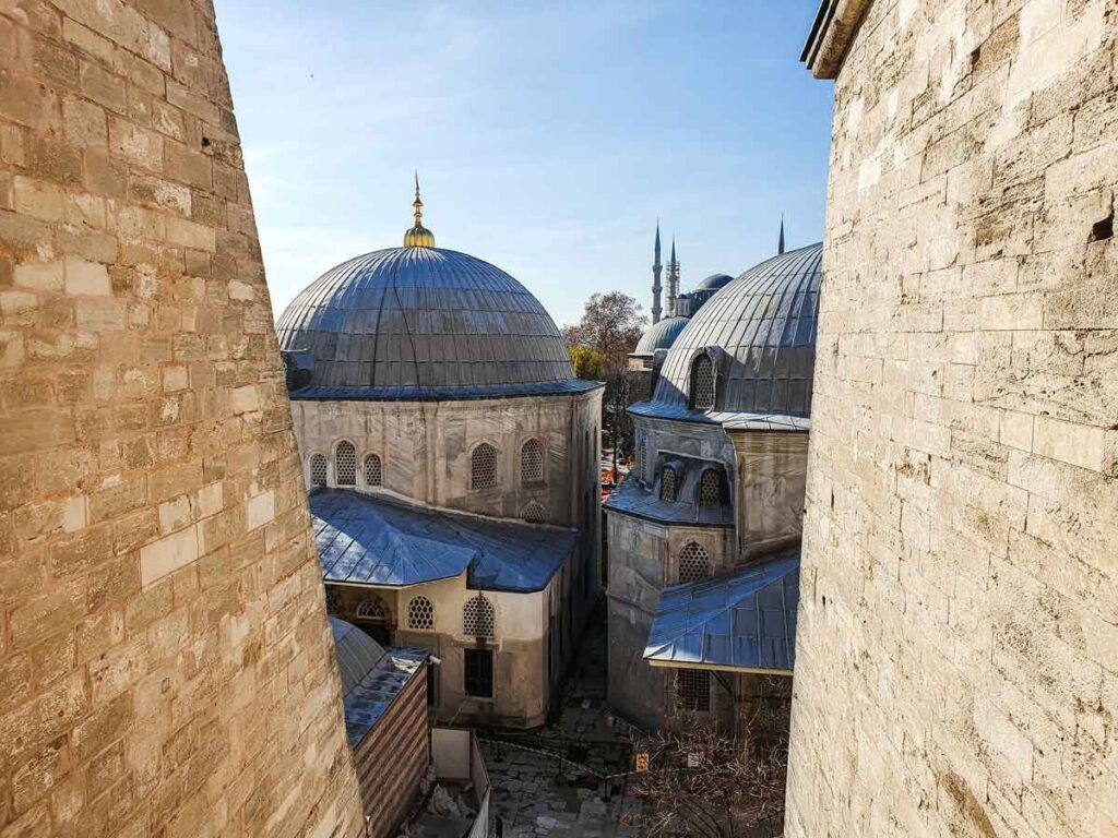 The blue domes of Hagia Sofia seen between two walls.